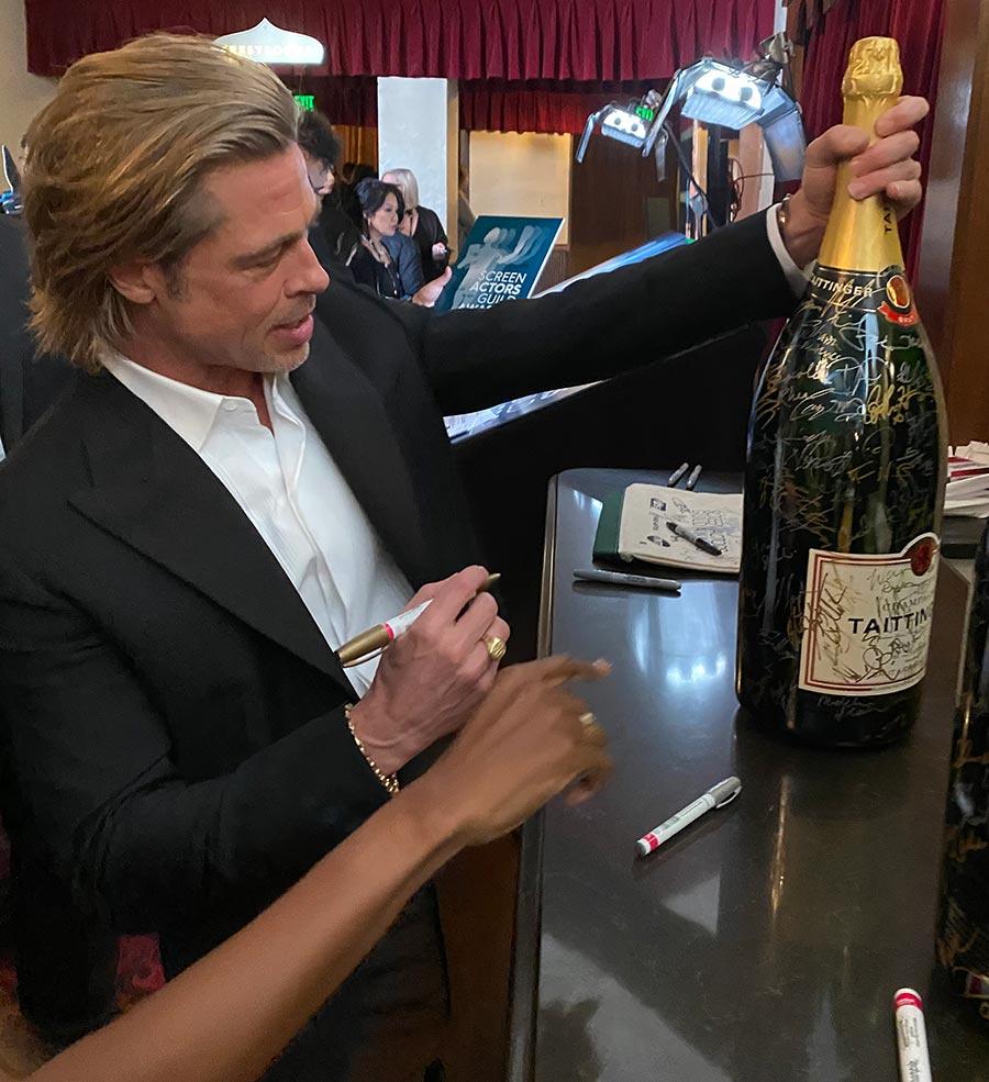 Hollywood actor Brad Pitt signing a large bottle of Taittinger Champagne at the 2020 SAG Awards